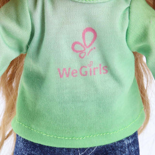 Close-up detail of the WeGirls logo printed on Anna doll's teal T-shirt